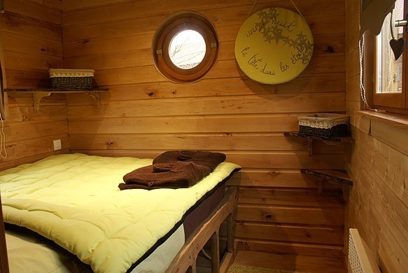 Lit rustique au fond de la roulotte.