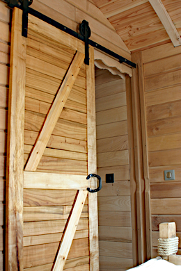 Porte sur rail avec roue de grange apparente.