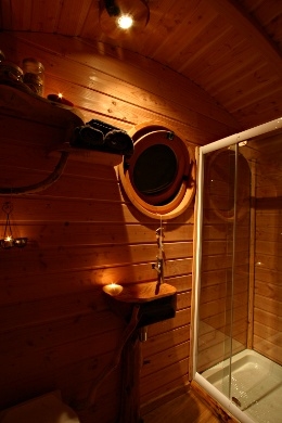 Détails de la salle de bain de la roulotte avec son lavabo en bois et sa cabine de douche.