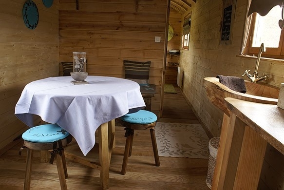 Aménagement de la roulotte: table du séjour ronde et porte d'entrée rectangulaire à petits carreaux.