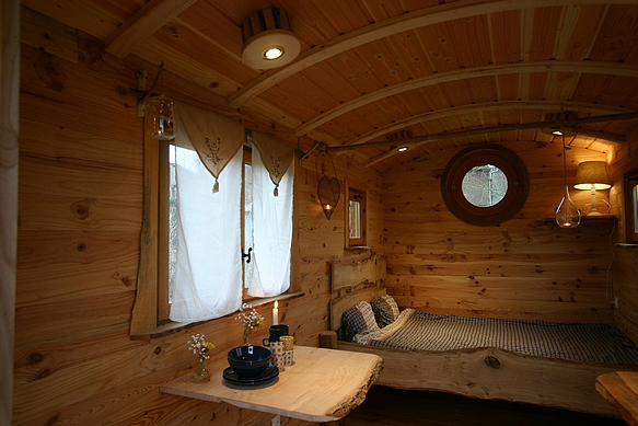 Roulotte avec un lit 2 personnes, un plan de travail et une table bergère.