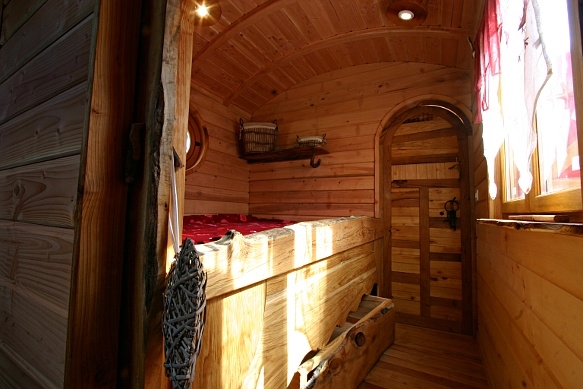 Chambre de la roulotte avec la porte cintrée artisanale.