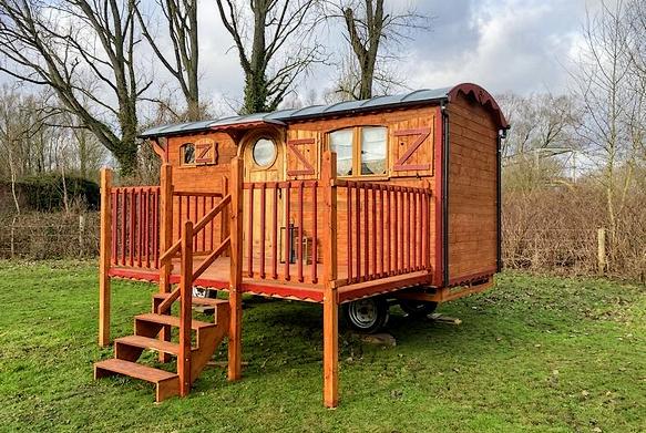 Petite roulotte à vendre avec une grande terrasse sur le côté.