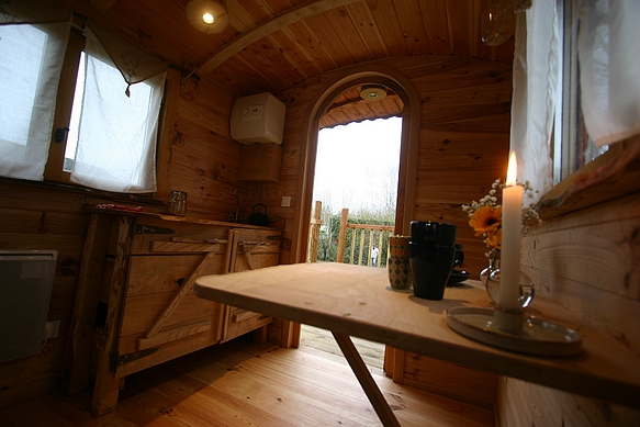 Vue de l'intérieur de la roulotte avec la petite table bergère ainsi que le plan de travail.