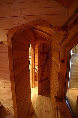 Couloire de la roulotte en bardage d'Aulne avec les portes artisanales cintrées.