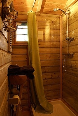 Salle de bain en bois de la roulotte avec rideaux de douche et bac à douche en grès.