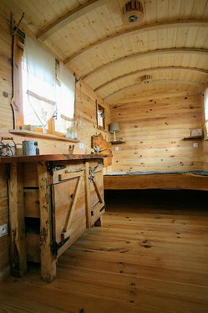 Intérieur de la roulotte avec chambre, coin cuisine et possibilité d'y installer une salle de bain et un toilette.
